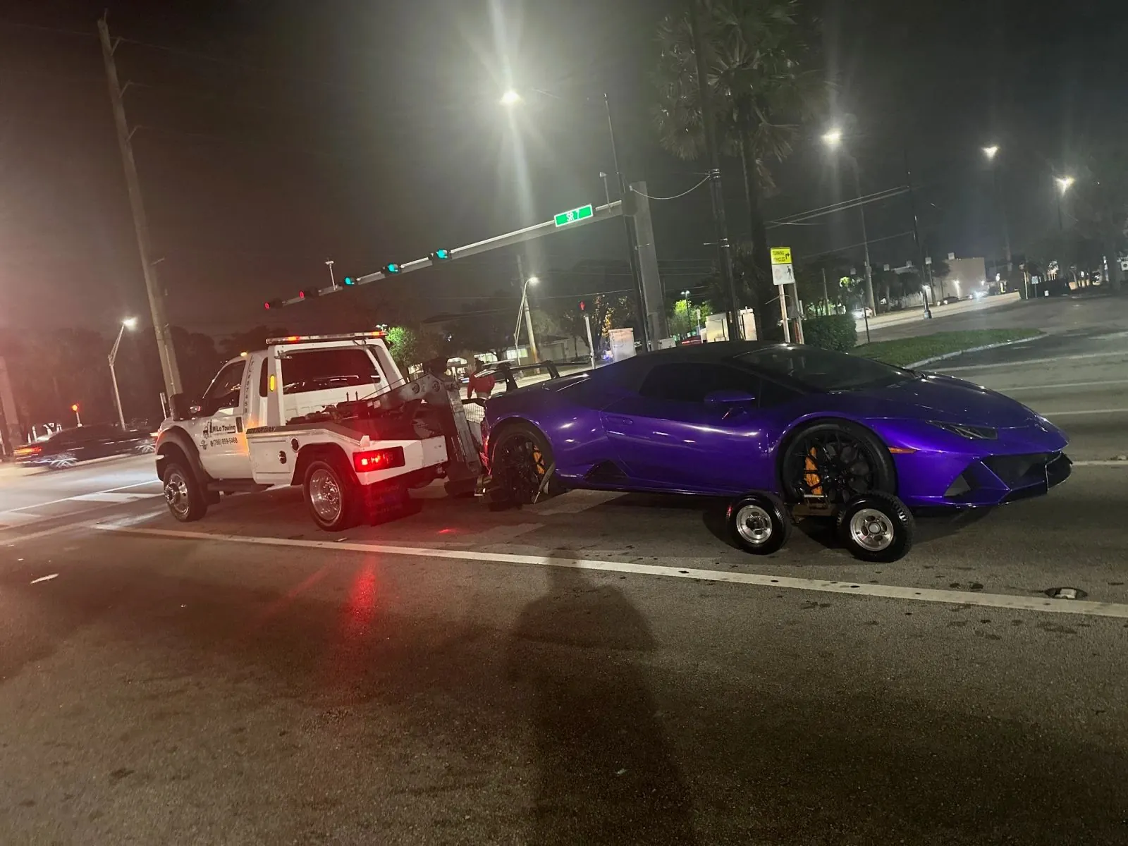Tow truck moving a car on wheel dollies at night in Lee County, FL